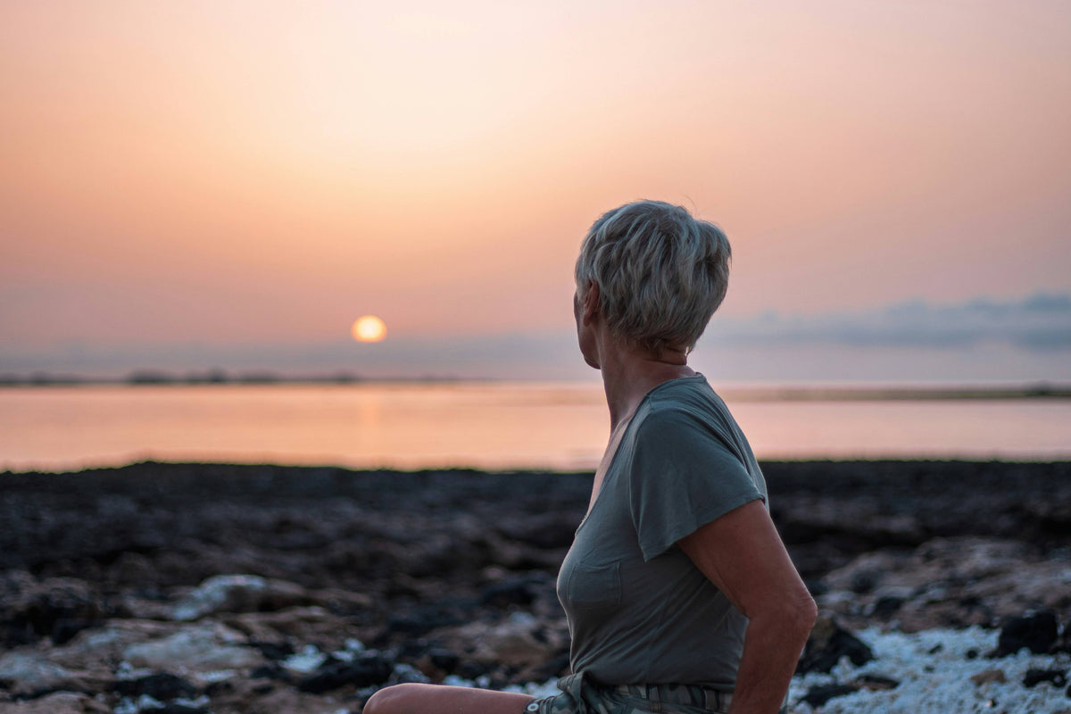 Water-based lubricant and a compact clitoral vibrator arranged on a blush background for a sex-after-menopause guide