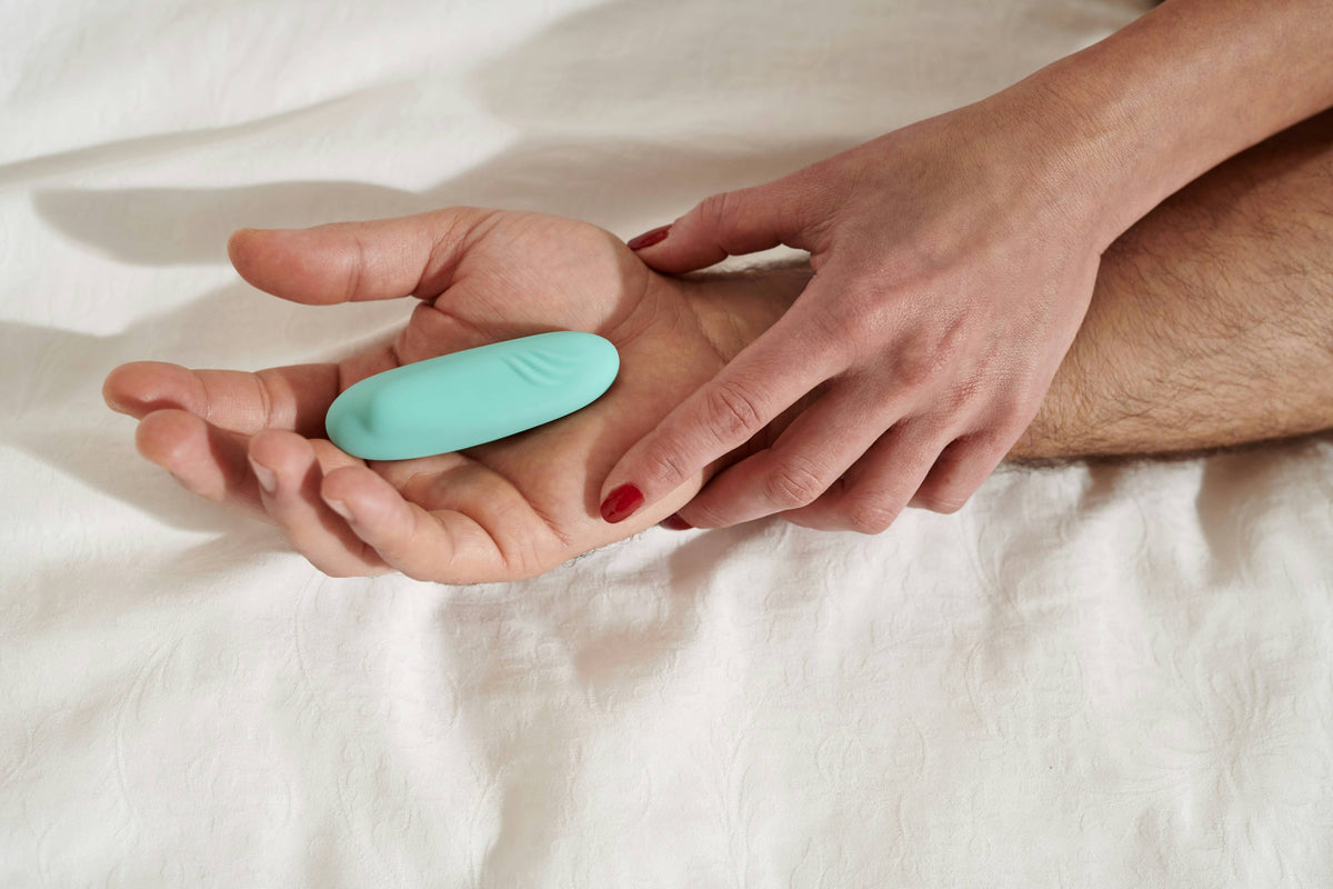 Silicone vibrator, glass dildo, metal plug and soft masturbation sleeve arranged on an elegant blush background