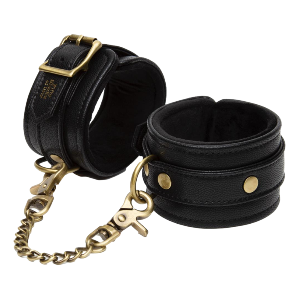 Fifty Shades Bound to You Ankle Cuffs with gold hardware shown flat with packaging, highlighting luxurious faux leather design.