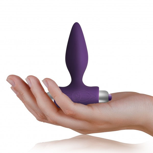 Purple vibrating anal plug held in hand to show compact size and smooth silicone texture