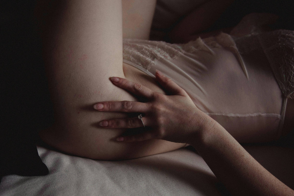 Water-based lubricant and a gentle external vibrator arranged on a soft blush bedside surface for a postpartum-intimacy guide