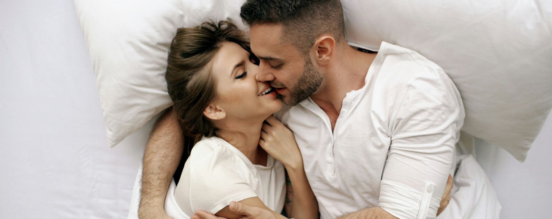 couple intimately in bed sharing a kiss