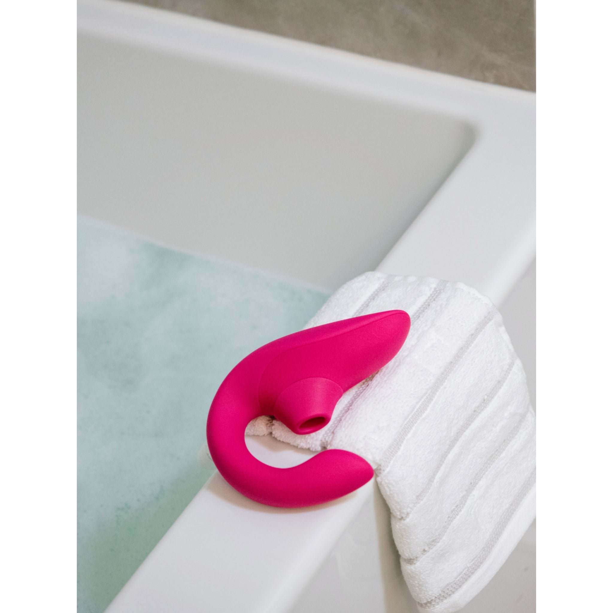 Unboxed Womanizer Vibrator resting on the side of the bath